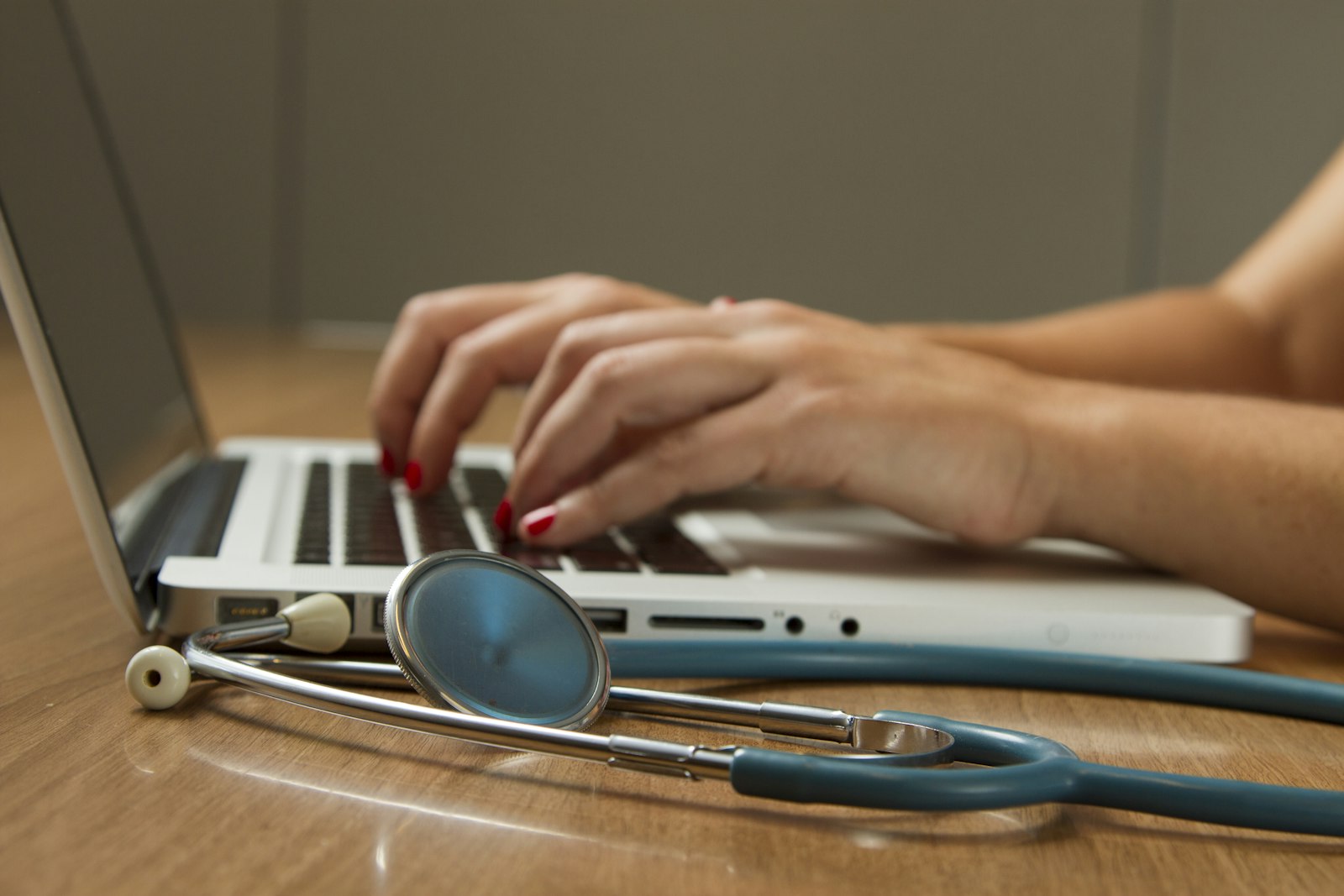 Medical billing specialist entering claims on a laptop beside a stethoscope